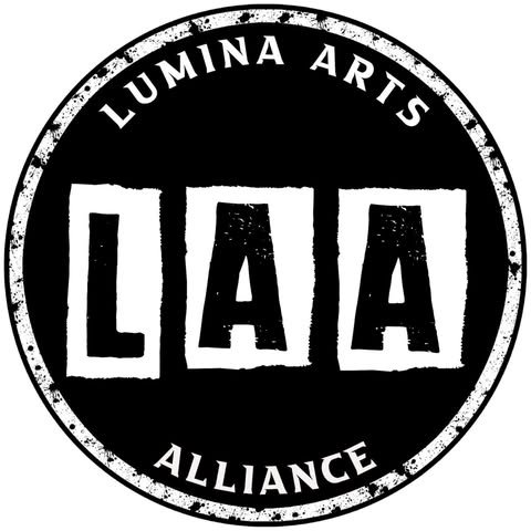 A circular black and white logo with 'LUMINA ARTS' at the top, 'ALLIANCE' at the bottom, and three large letters 'LAA' in the center.